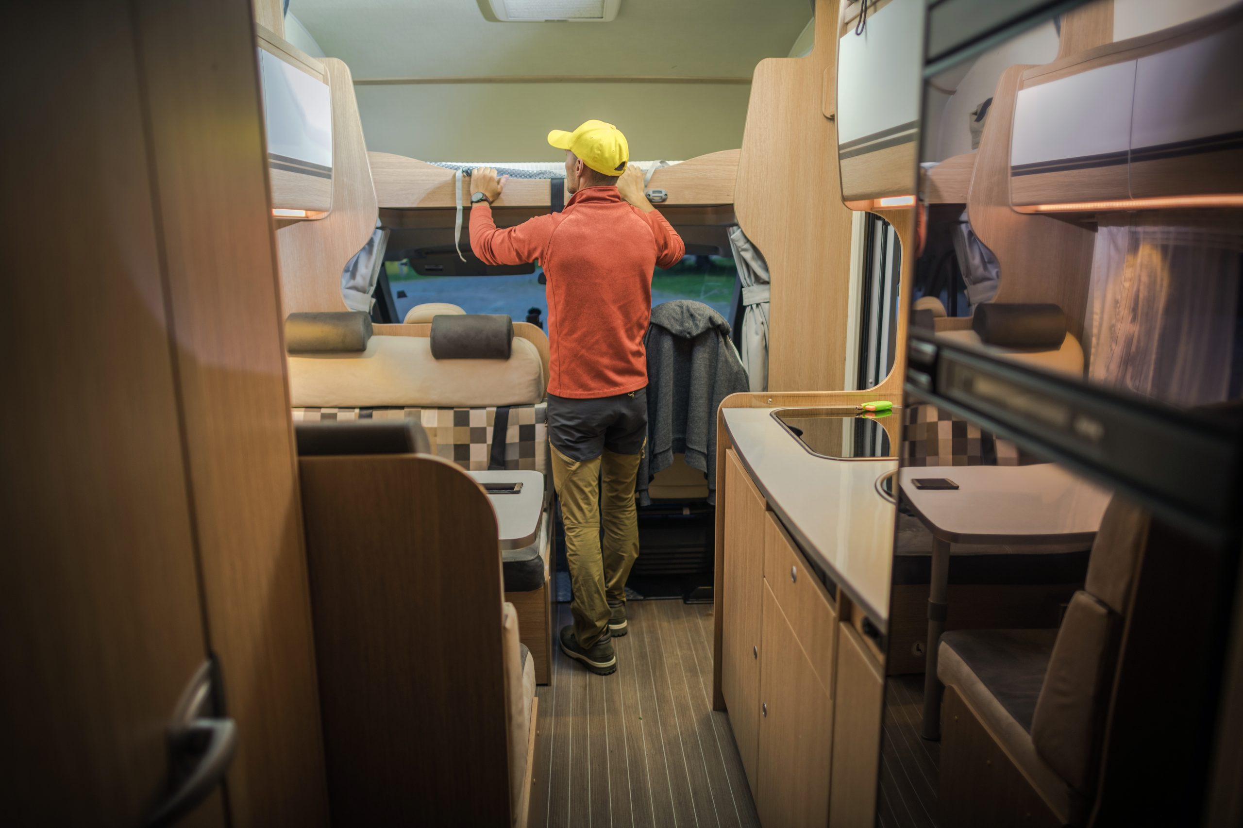 Men Preparing RV For Summer Season Looking on Bunk Bed. Modern Class C Motorhome Interior. Recreational Vehicle.