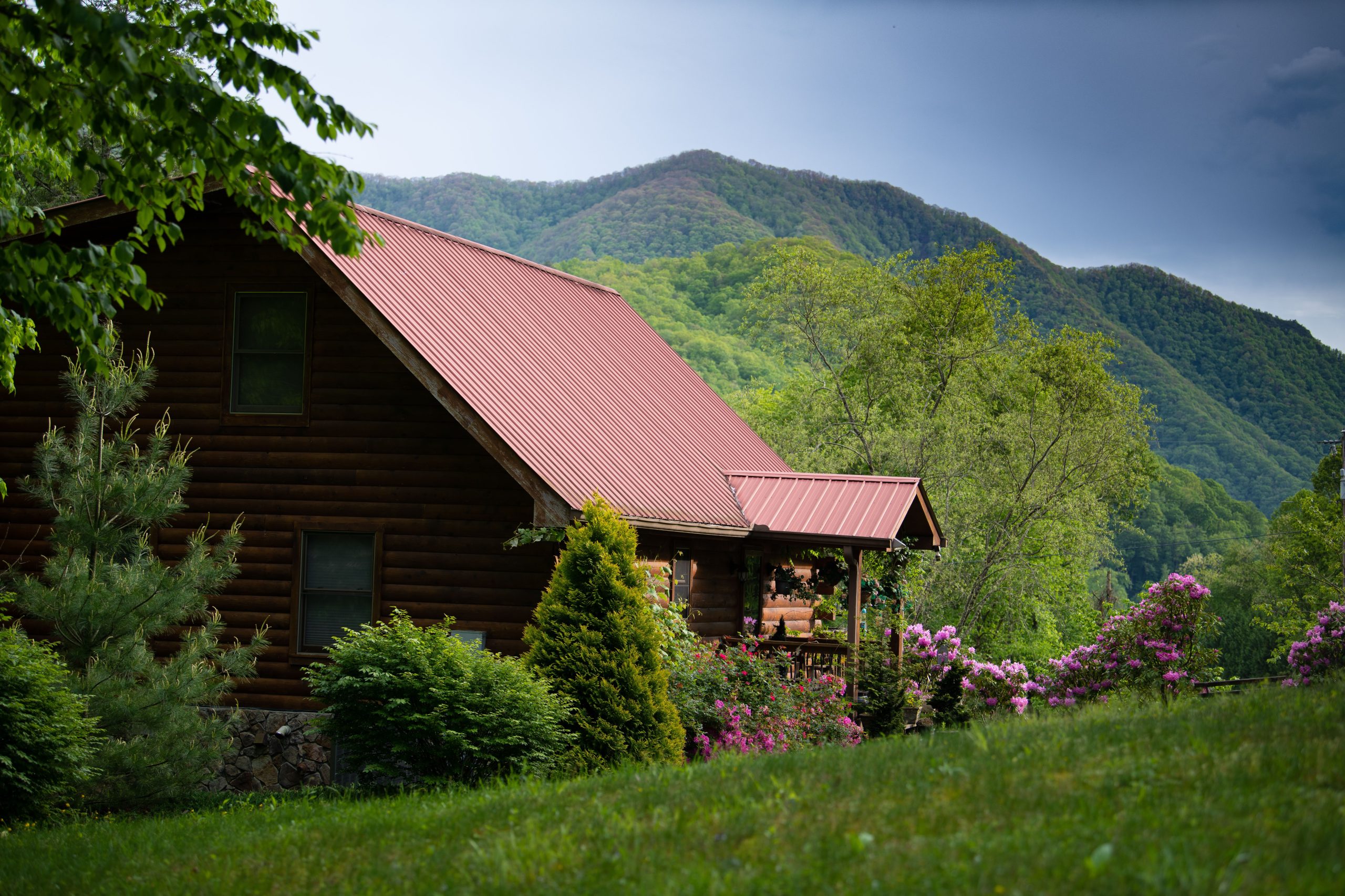 A closeup of a house in mountains covered in greenery under the sunlight